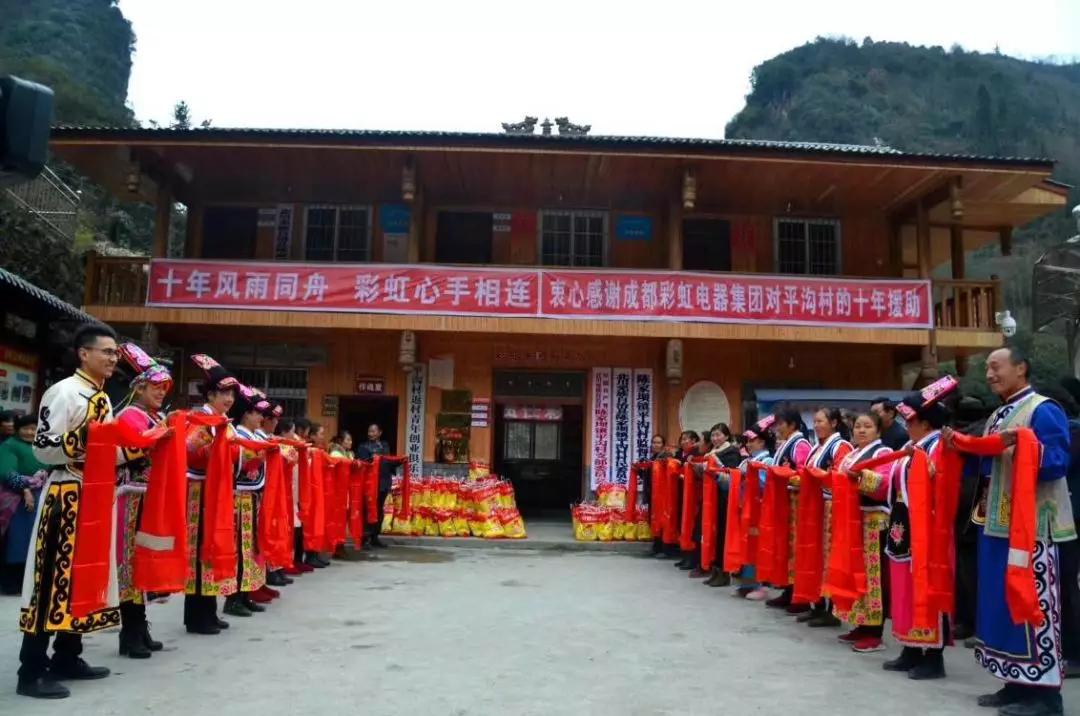 怀感恩之心，平沟村村民手持羌红在万搏（中国）万搏公司援建的平沟村便民服务楼前热情等待万搏（中国）万搏亲人们的到来